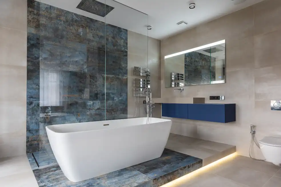 Modern master bathroom renovation featuring dramatic blue-patina tiles, freestanding tub, and luxury rain shower with ambient lighting